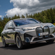 A photo of a BMW iX electric SUV driving on a highway.